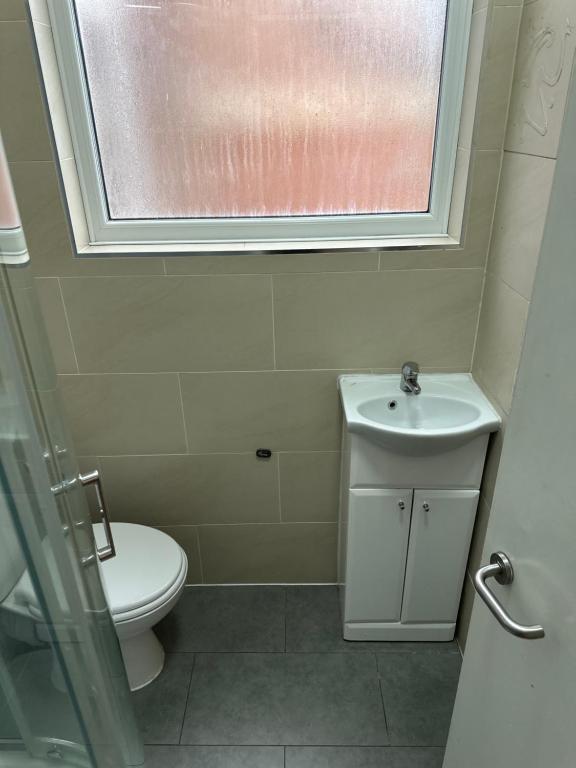 Comfort Stays - Streatham High Road في لندن: حمام مع مرحاض ومغسلة ونافذة