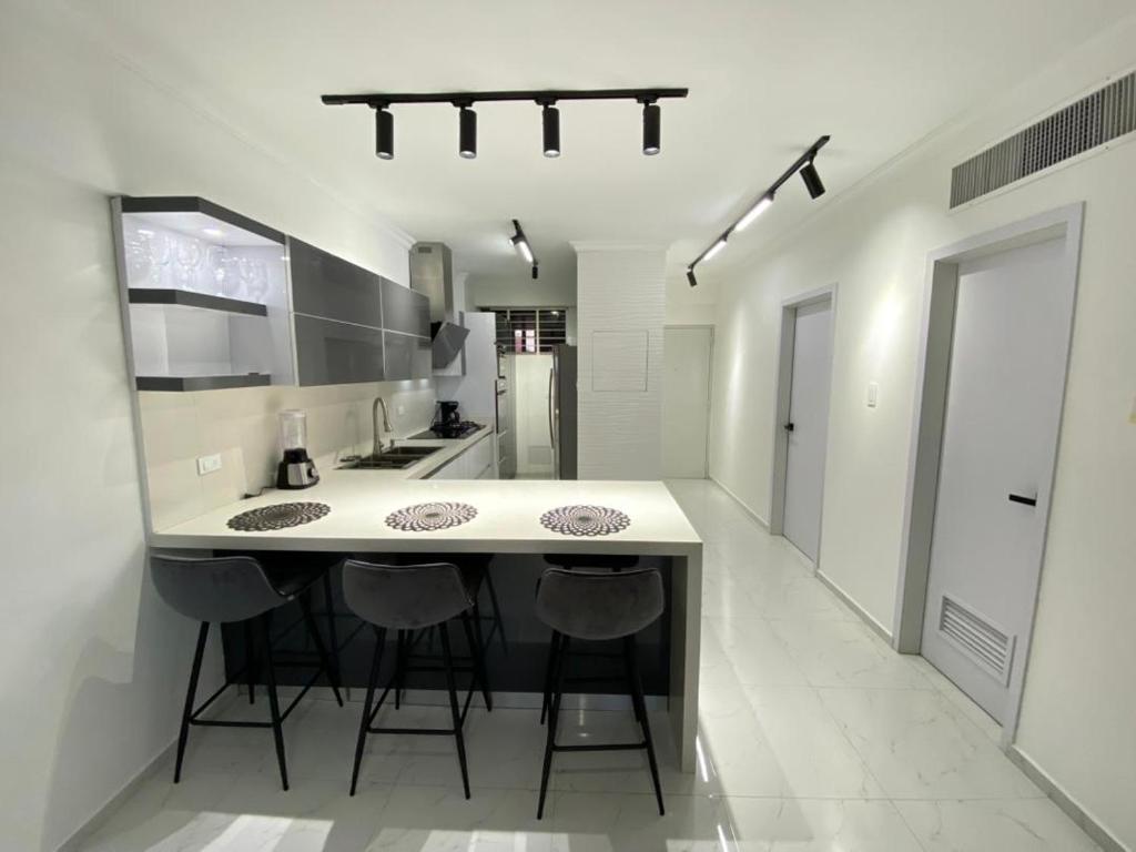 a kitchen with a large white counter and stools at Apartamento Exclusivo Av Principal LECHERIA in El Morro de Barcelona