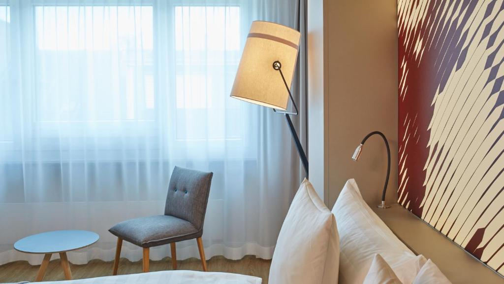 a bedroom with a bed and a chair and a lamp at Hotel Wettstein in Basel