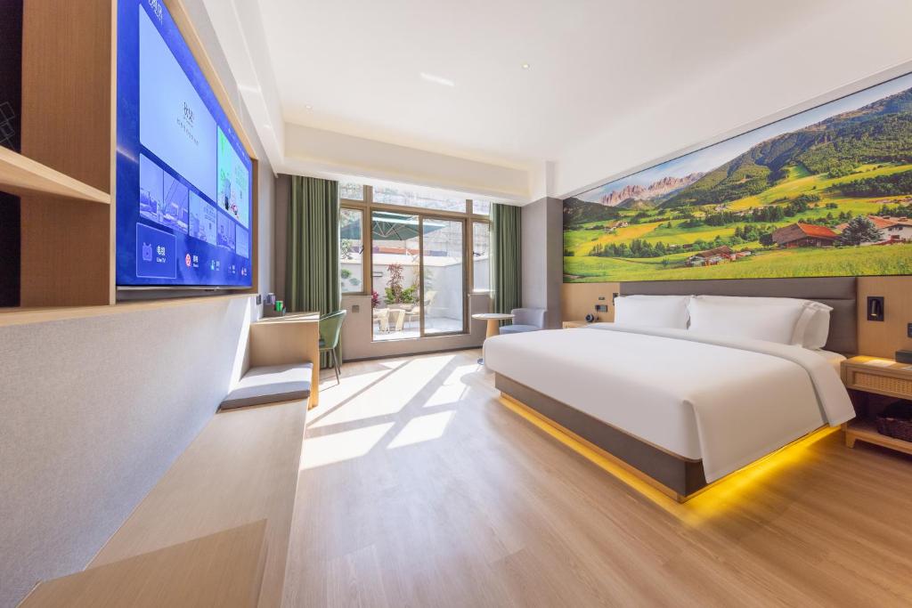 ein Schlafzimmer mit einem großen Bett und einem großen Fernseher in der Unterkunft Qiuguo Garden Hotel in Dongguan