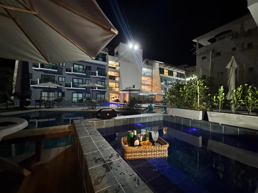 een mand met eten die 's nachts naast een zwembad staat bij Bela Vista Residence Piscina Privativa in Porto De Galinhas