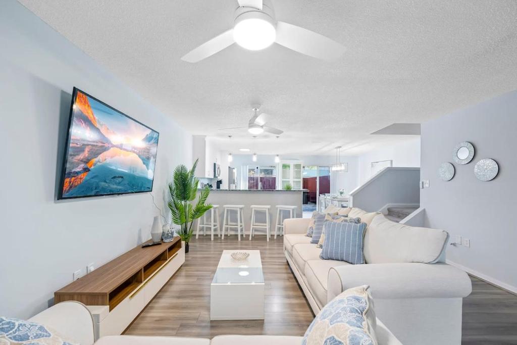 a living room with a white couch and a kitchen at Stylish Townhome w Hot Tub 5 Min Walk to Beach in Cape Canaveral