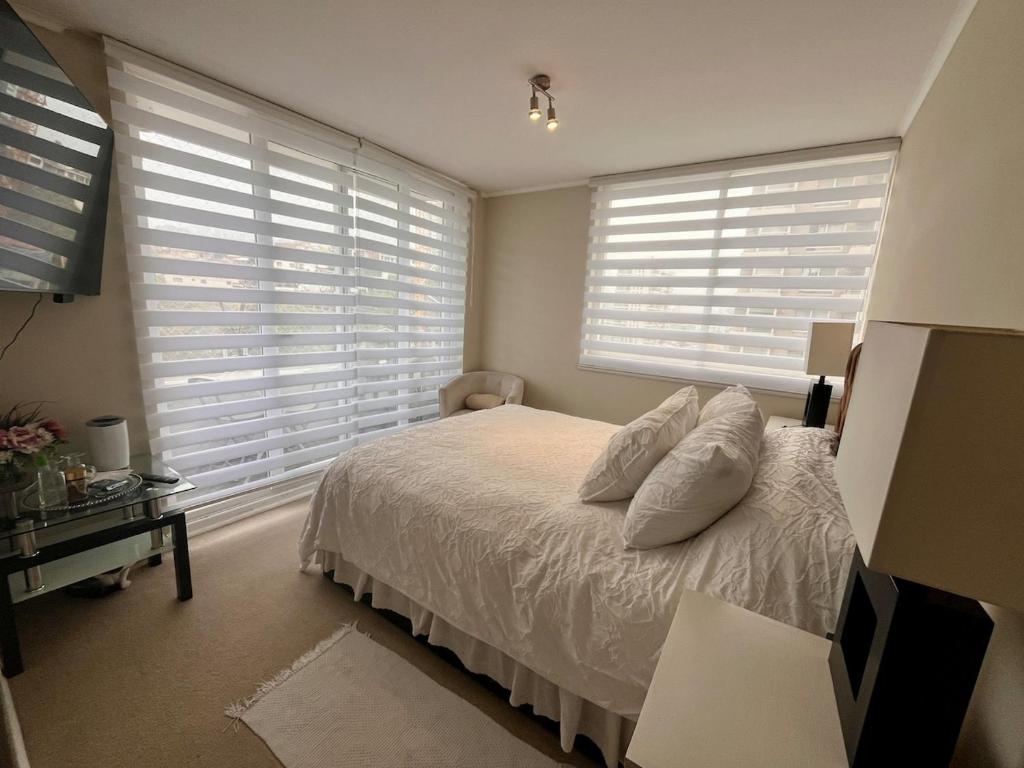 a bedroom with a bed with white pillows and windows at Alojamiento Entero en Centro de Viña del mar in Viña del Mar