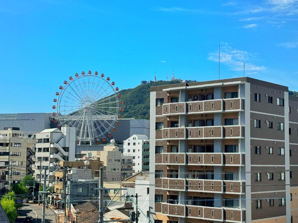 Private Retreat Nagasaki Vogelnest 2階貸切屋上テラス貸切長崎スタジアム5分 في ناغاساكي: عجل فيريس في خلفية المدينة