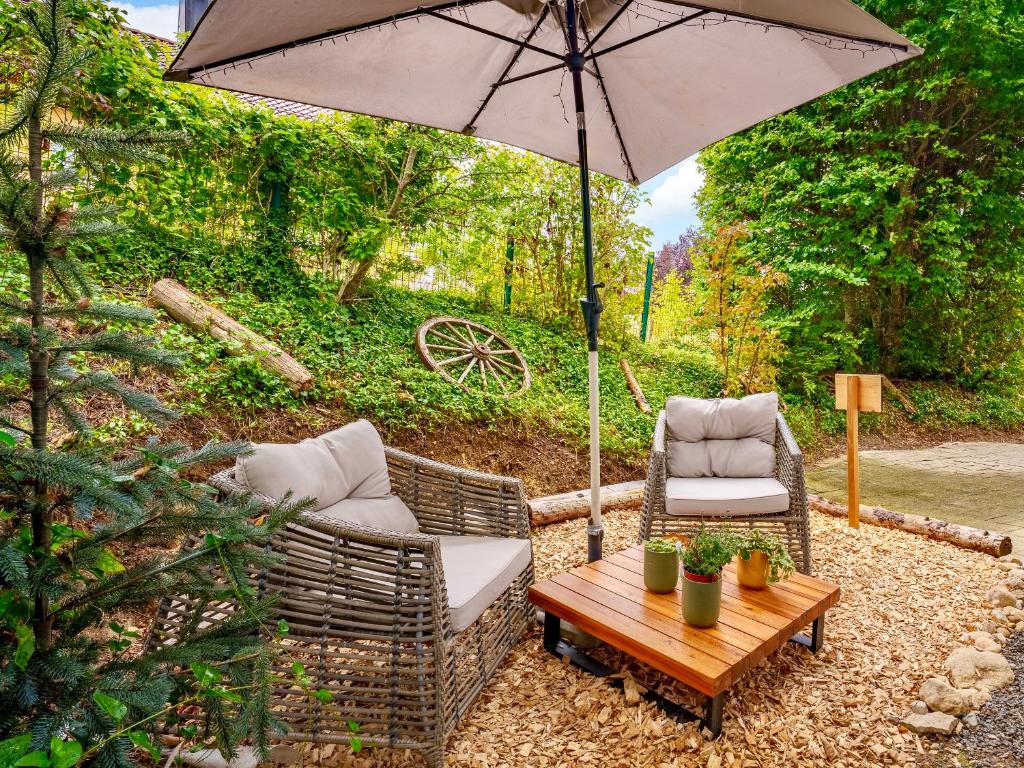 a patio with two chairs and a table with an umbrella at Beautiful studio - private garden, EV, breakfast - Chalet Hug studio in Arzier