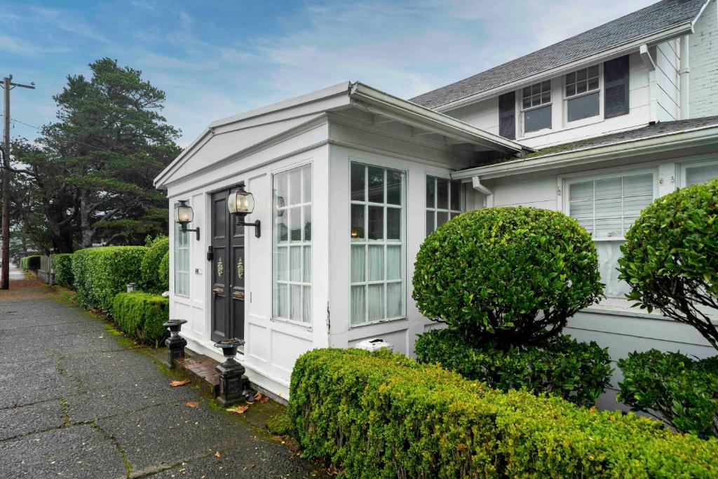 une maison blanche avec une porte d'entrée et des buissons dans l'établissement Pacific Way Villa, à Gearhart
