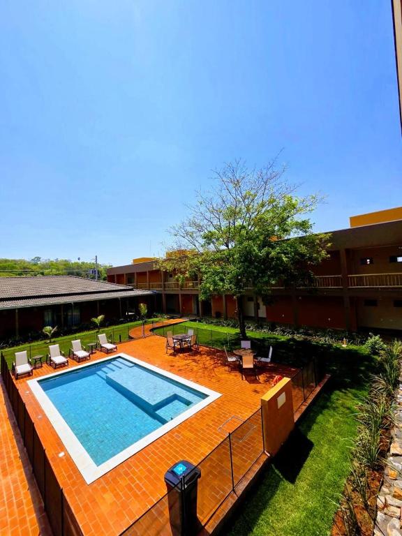 a swimming pool in a courtyard with chairs and a building at Pousada Maritaca in Bonito