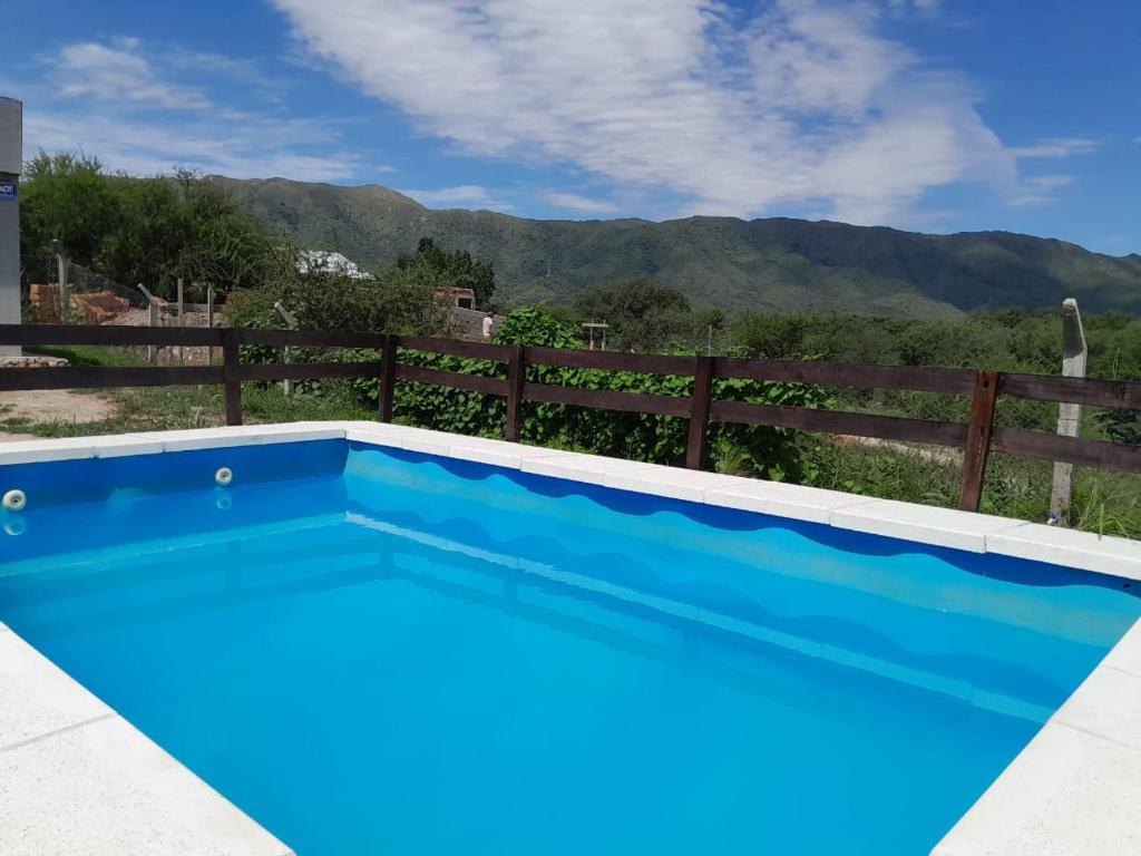a blue swimming pool with a fence and mountains in the background at Mateo y Stella 3 in Bialet Massé