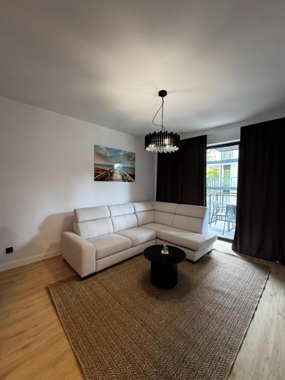 a living room with a white couch and a table at Apartament Morzlive in Ustronie Morskie