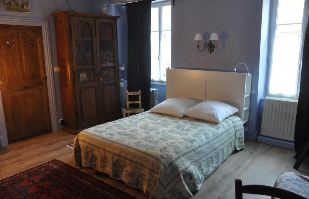 una camera da letto con un letto in una stanza con finestre di Vaste chambre au centre du bourg a Saulieu