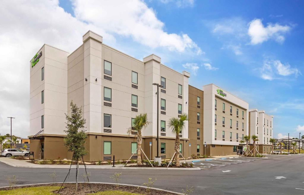 a large white building with palm trees in a parking lot at Extended Stay America Premier Suites - Jacksonville - Airport in Jacksonville