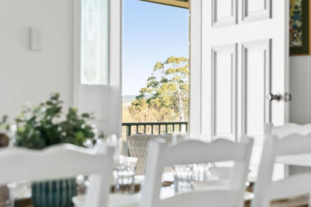 ein Esszimmer mit weißen Tischen und Stühlen und einem Fenster in der Unterkunft Mountain Views Milton - renovated home near village in Milton