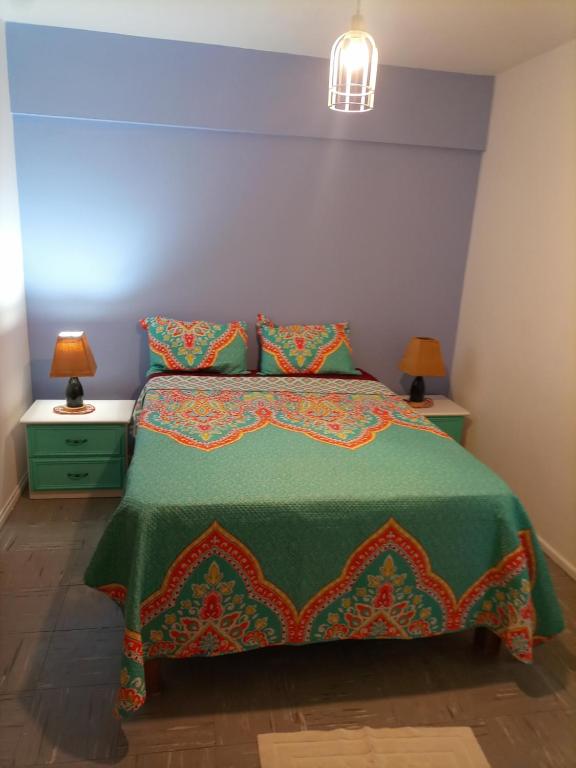 a bedroom with a bed with a green bedspread and two lamps at Departamento todo a mano parque central in La Cieneguita