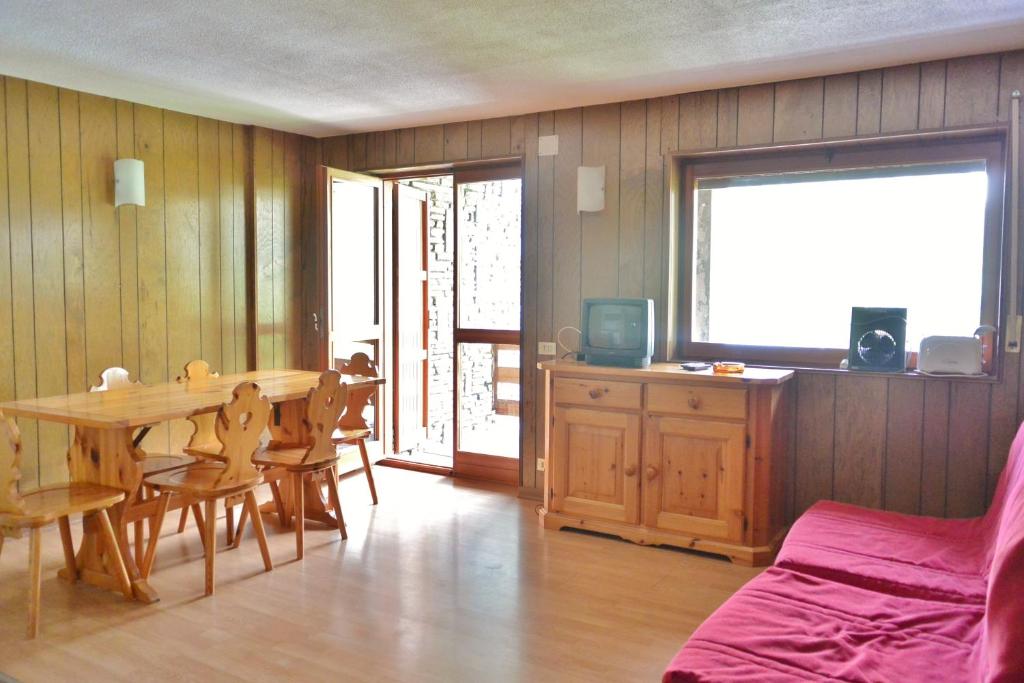 sala de estar con mesa, sillas y cama en Maison de Vacances Rododendro, en Breuil-Cervinia
