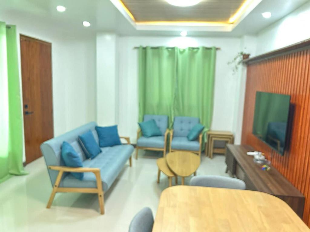 a living room with blue furniture and a flat screen tv at Cozy Baguio House Near Camp John Hay in Baguio