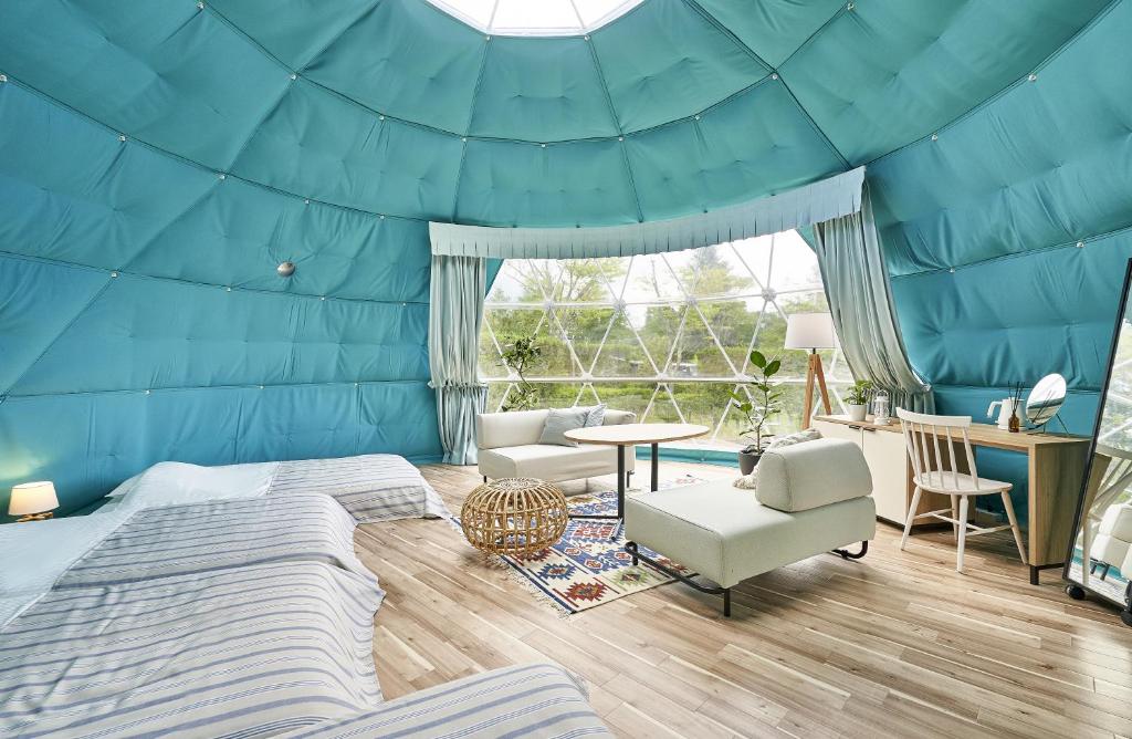 ein blaues Zimmer mit einem Bett, einem Tisch und Stühlen in der Unterkunft Glampseason in Sendai