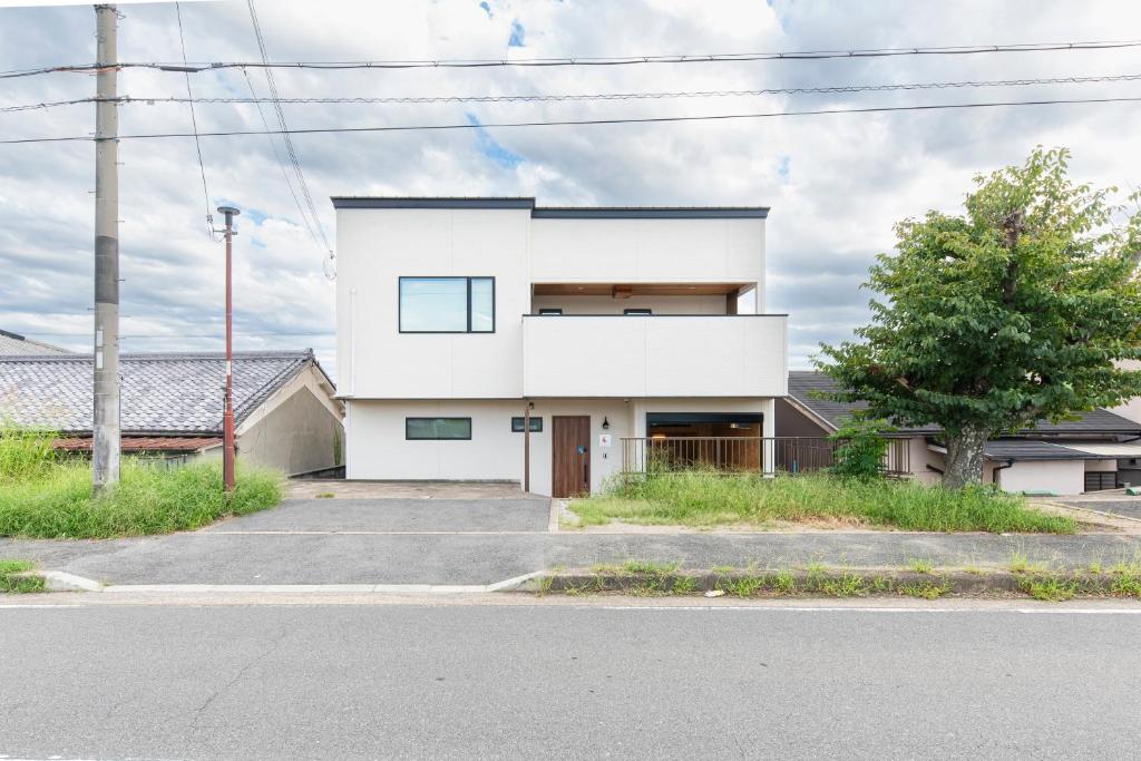a white house on the side of a street at Kotohaku 木津町 in Kizugawa