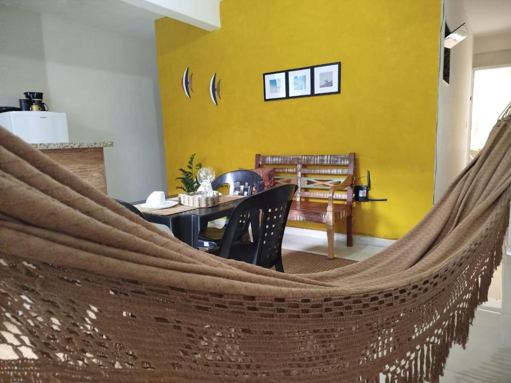 uma rede em um quarto com uma mesa e uma parede amarela em Loft aconchegante Estou em Arraial em Arraial do Cabo