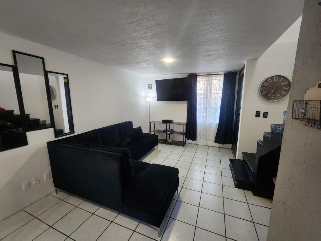 a living room with a couch and a clock on the wall at Casa entera, elegante, moderna in Guadalajara