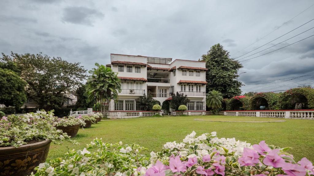 a large white house with a yard with flowers at MIRANAMIN NEST Elegant Home, Indoor Plunge Pool, Pet-Friendly, with Rooftop, Kitchens, Self-Service Breakfast - Ideal for Reunions, Team Building, Intimate Gatherings in Manila