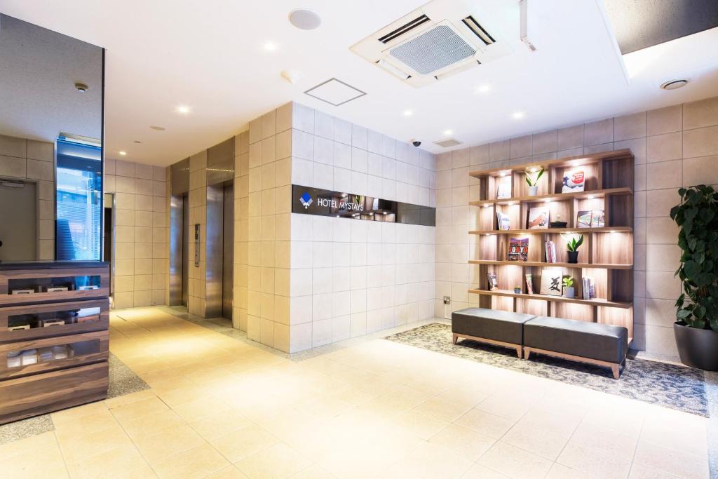 een lobby met een bank en een boekenplank bij HOTEL MYSTAYS Kanda in Tokyo