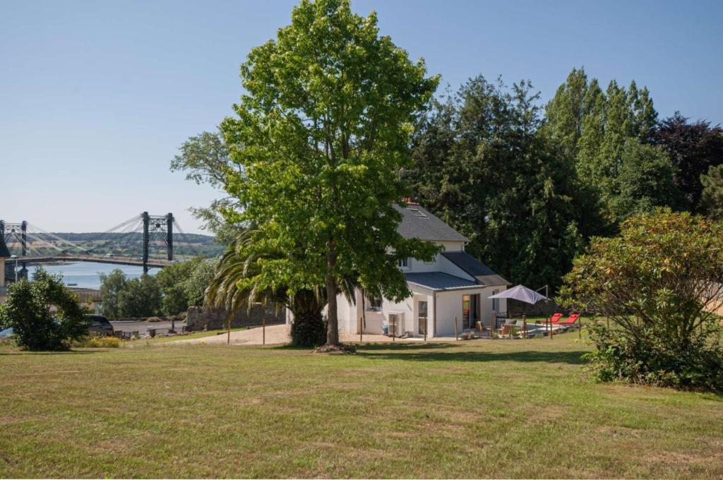 a house in a field with a tree and a bridge at St christophe in Lézardrieux