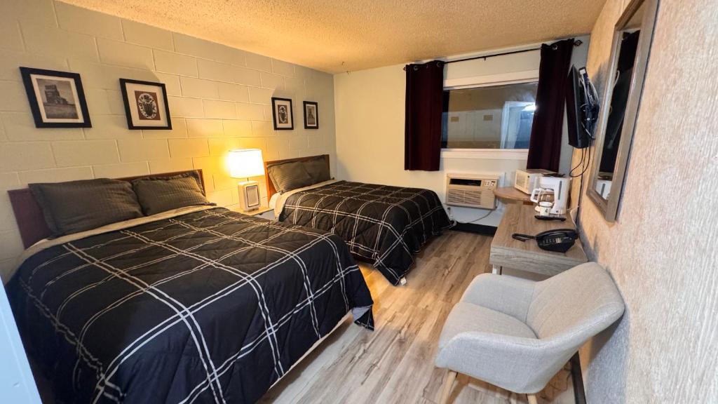 サスカトゥーンにあるConfederation Innのベッド2台と椅子があるホテルの部屋