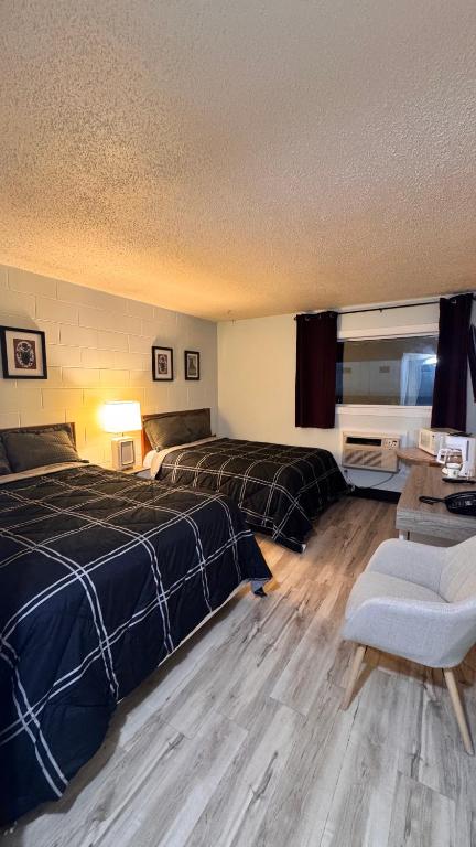 a bedroom with two beds and a table and a chair at Confederation Inn in Saskatoon