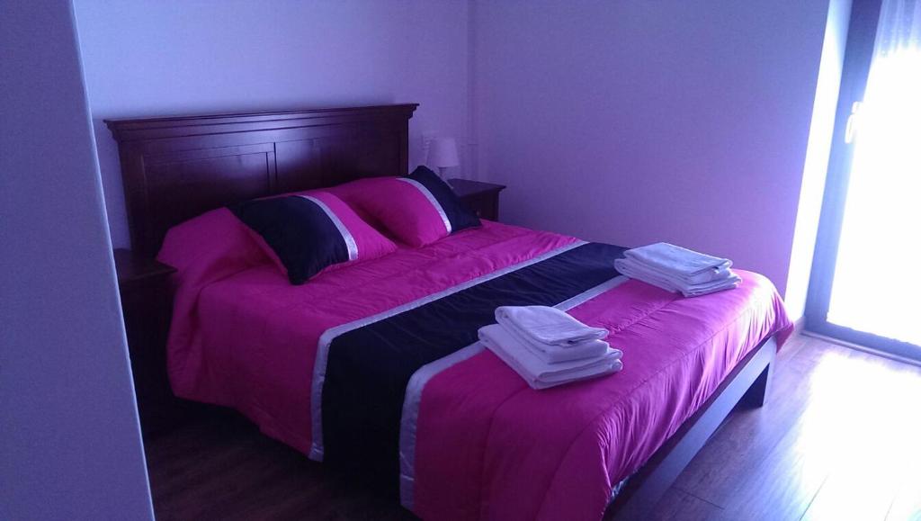 a bedroom with a pink bed with two towels on it at Casa Rural El Zumaque in Pereña
