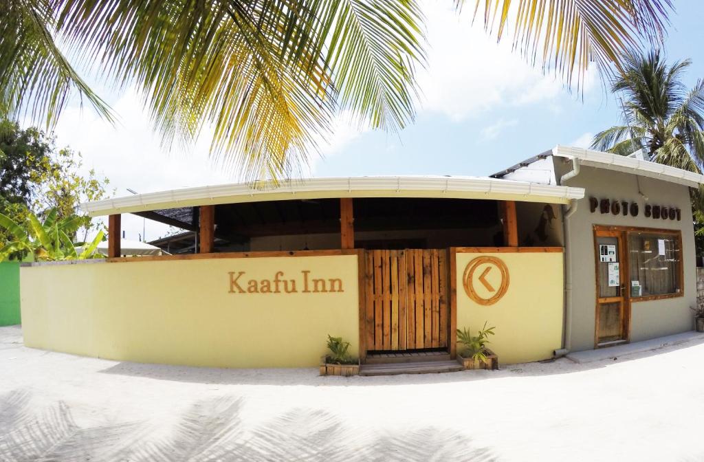 un edificio sulla spiaggia con una palma di Kaafu Inn Guraidhoo a Guraidhoo