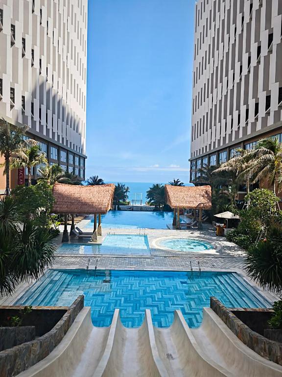 a swimming pool in the middle of two tall buildings at Apec Mandala Sea View Bathtub by MLT in Mui Ne