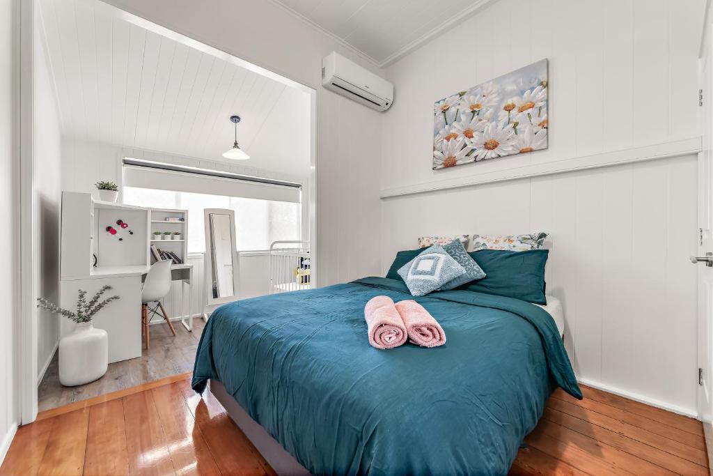 a bedroom with a bed with two pink slippers on it at Spacious and Charming Queenslander in Ipswich in Bundamba