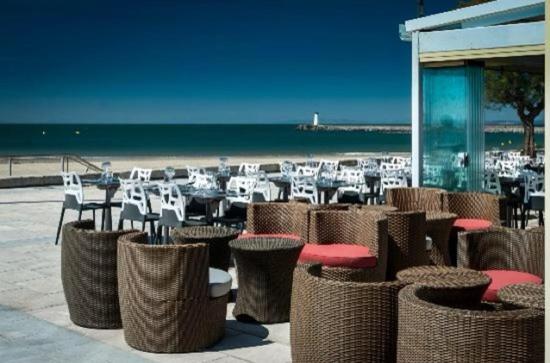 eine Gruppe von Tischen und Stühlen am Strand in der Unterkunft Hôtel Restaurant le Voilis in Le Grau-dʼAgde