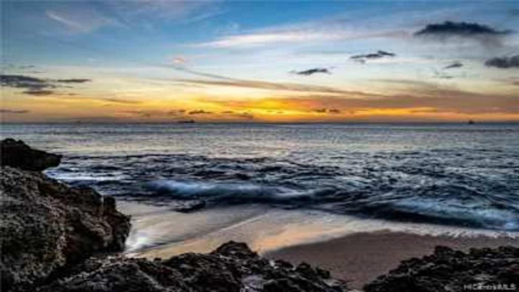 a sunset over a beach with rocks and the ocean at Beautiful 3 Bedroom Villa in Honokai Hale