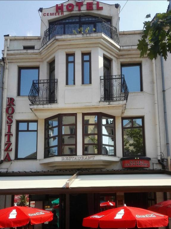 a building with red umbrellas in front of it at Family Hotel Rositsa in Sevlievo