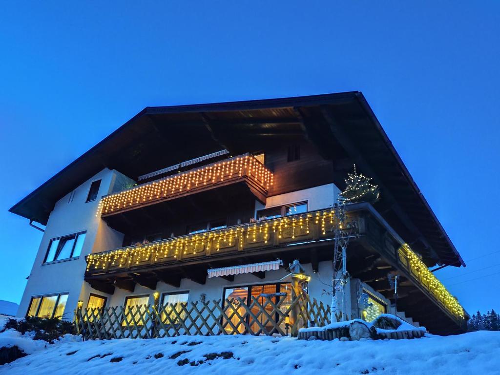 a building covered in christmas lights in the snow at Privatzimmer Pendl in Abtenau