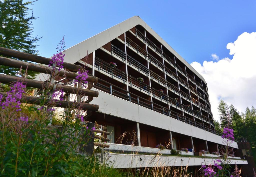 un edificio de oficinas con flores púrpuras en primer plano en Appartamenti La Maison de Vacances, en Breuil-Cervinia