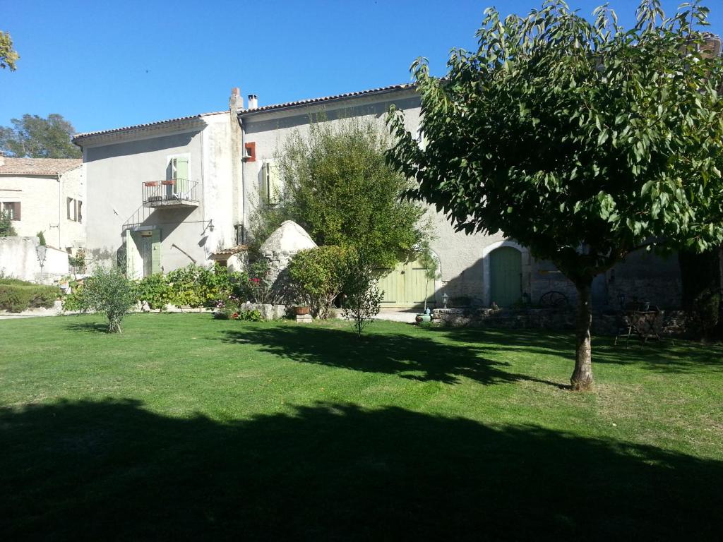 una casa con un giardino verde con un albero di Grange Voutée avec jardin a Mane