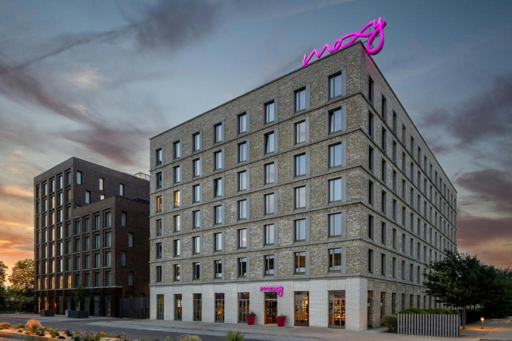 a building with a neon sign on top of it at Moxy London Excel in London