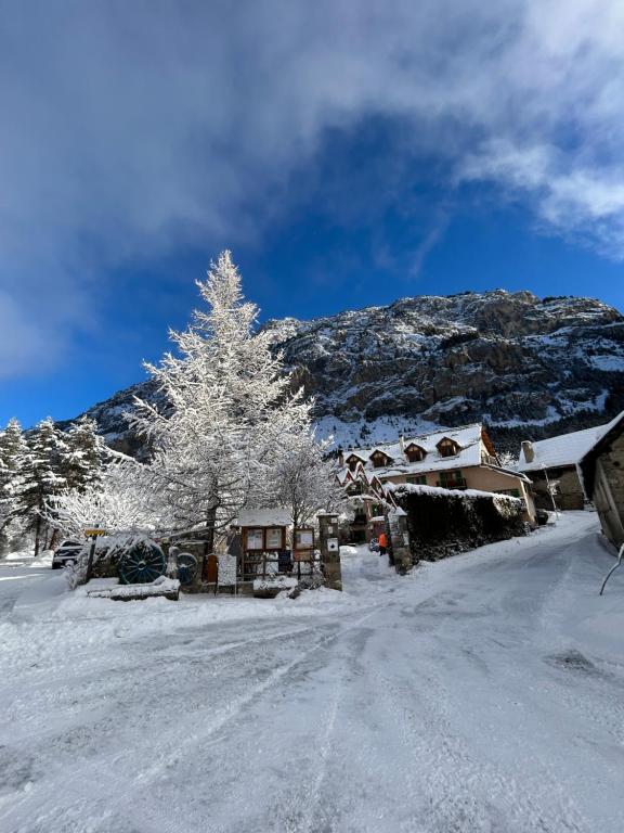 una casa cubierta de nieve con un árbol y una montaña en Auberge La Cleida, en Névache