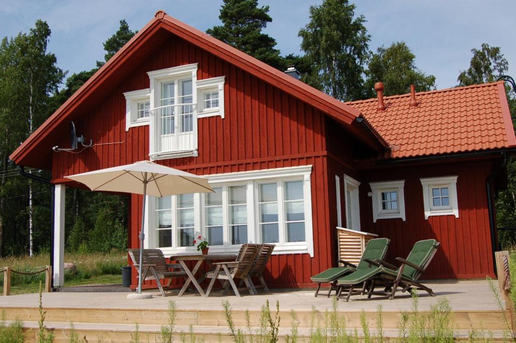 a red house with a table and chairs and an umbrella at Holiday Cottage Tiira in Raseborg
