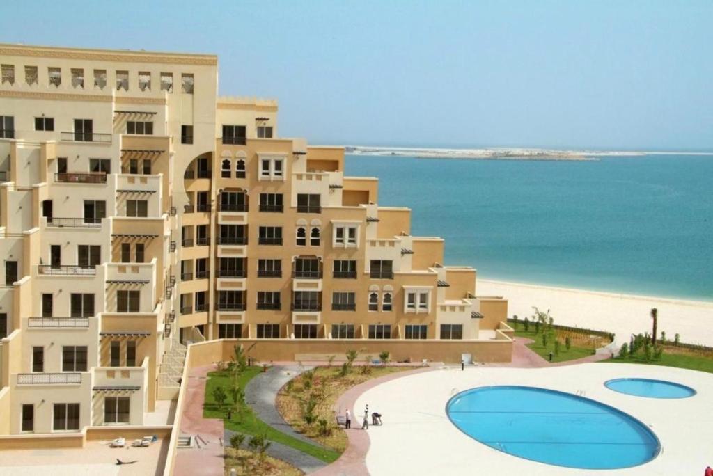 a large building next to a beach with a pool at Beachfront Luxury Stay with private beach 2 bedroom in Ras al Khaimah