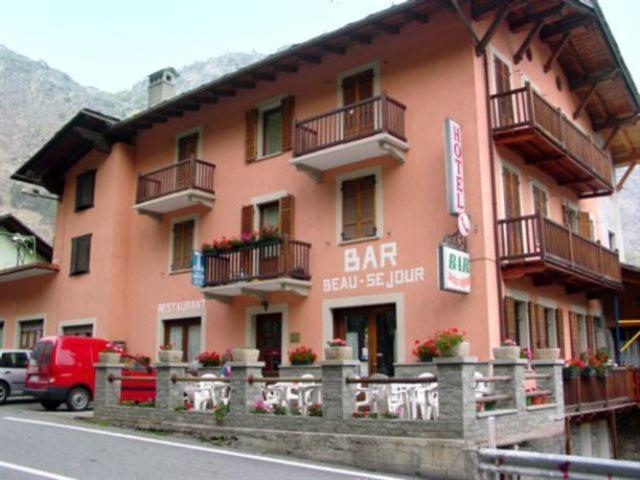 a pink building with a bar on the side of it at Hotel Beau Sejour in Arvier