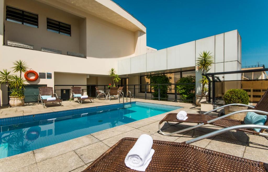 a swimming pool with chairs next to a building at Transamerica Executive Jardins in Sao Paulo