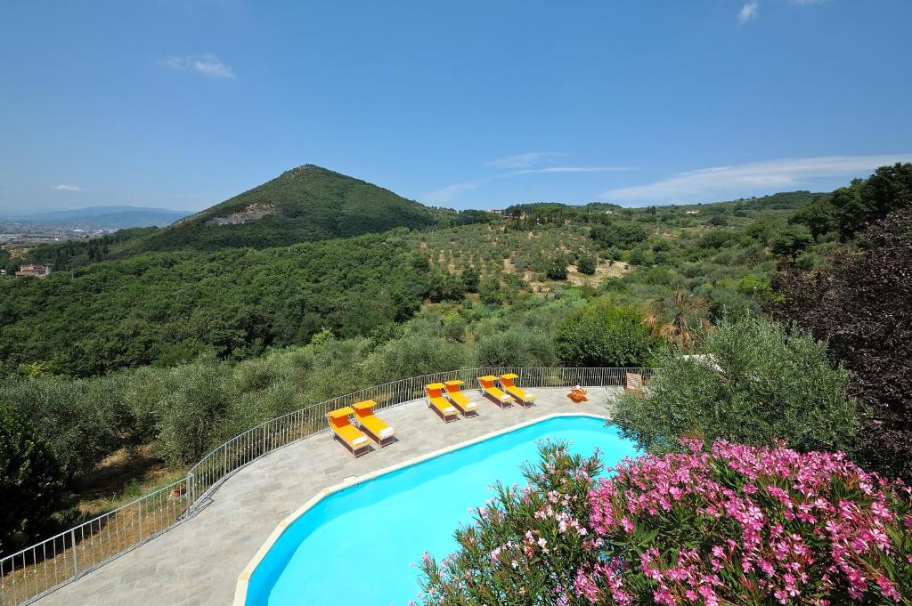 una piscina con sedie a sdraio e montagne sullo sfondo di Le Maggioline a Monsummano