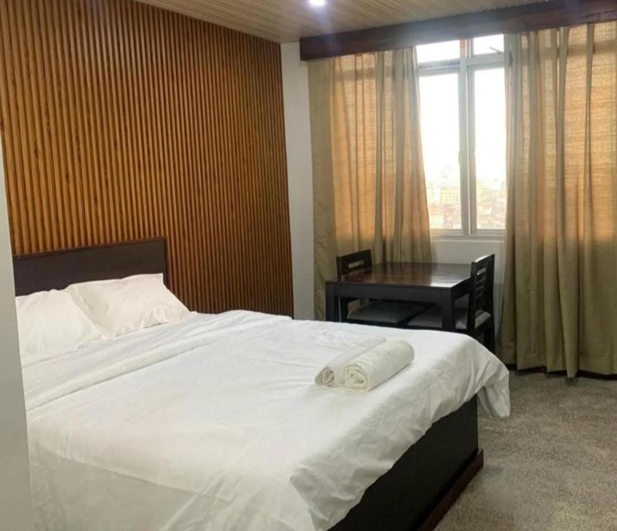 a bedroom with a white bed with a desk and a window at Serene haven in Kohīma