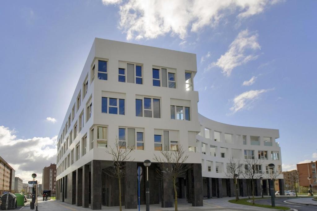 um edifício branco com janelas azuis numa rua em Apartamentos Irenaz em Vitoria-Gasteiz