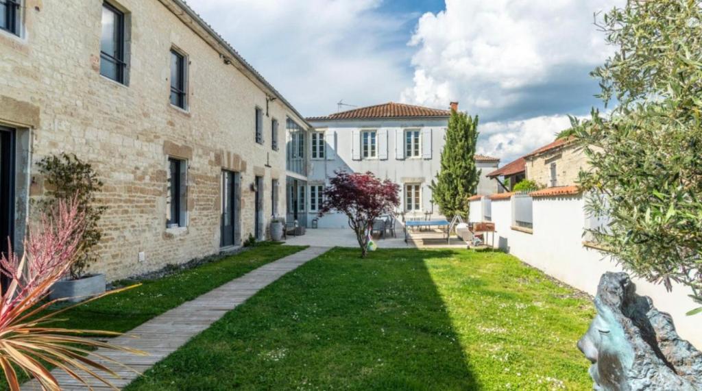 a courtyard of a house with a grass yard at Domaine Ericarclem in Aigrefeuille-dʼAunis