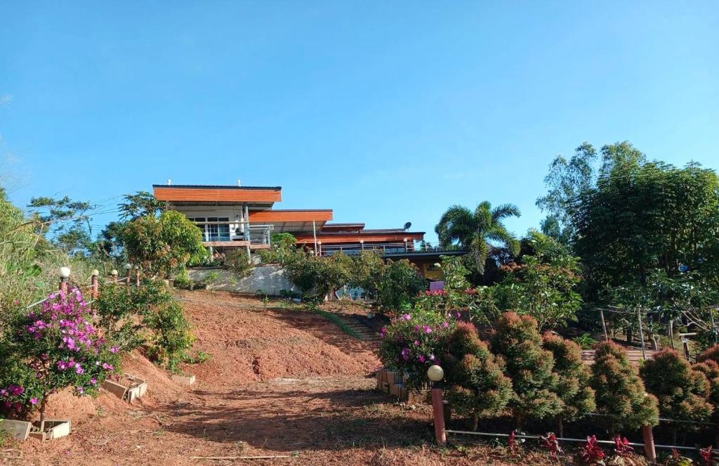 a house on top of a hill with trees and flowers at สิรีรินทร์ ภูหมอก in Khao Kho