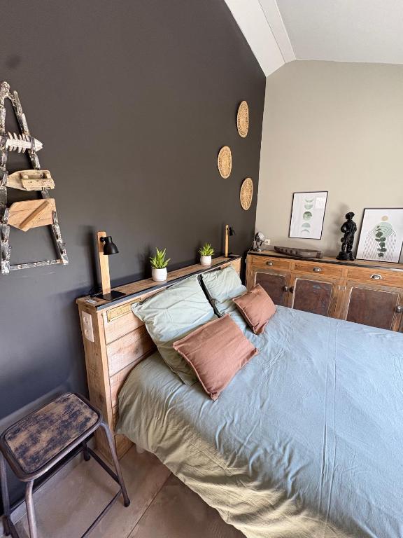 a bedroom with a bed with blue sheets and a chair at Pigeonnier des Banons in Puimoisson